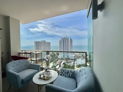 Stunning balcony view with modern seating overlooking cityscape and ocean horizon.