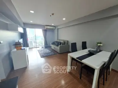 Spacious modern living room with balcony and dining area, featuring sleek furniture and wooden flooring.