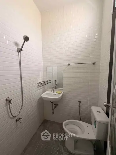 Compact modern bathroom with white tiles and essential fixtures, ideal for urban living.