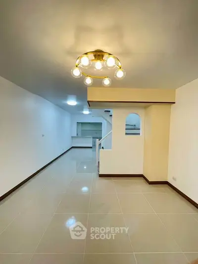 Spacious open-plan living area with modern lighting and tiled flooring, perfect for family gatherings.