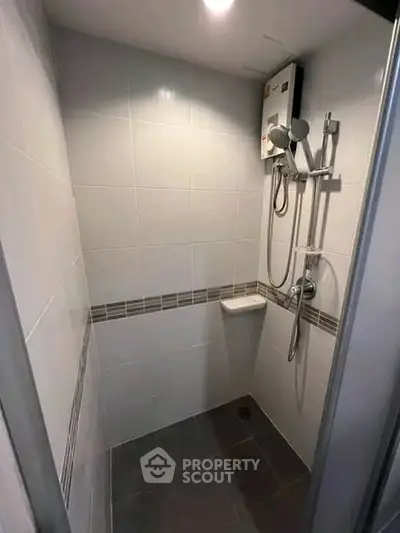 Compact bathroom with modern shower and water heater in a sleek tiled design.
