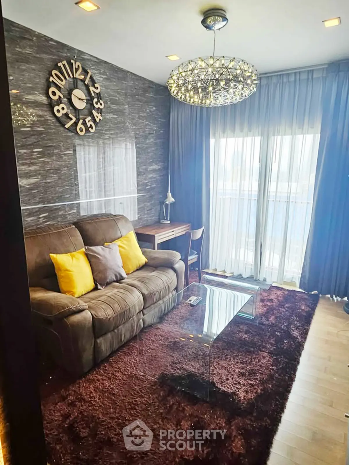 Stylish living room with plush sofa, modern chandelier, and floor-to-ceiling windows.