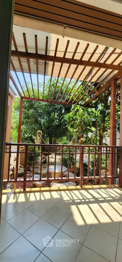 Charming balcony with wooden pergola and lush garden view, perfect for relaxation.