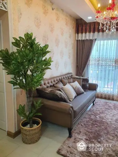 Elegant living room with classic tufted sofa, ornate wallpaper, plush rug, and a vibrant potted plant, complemented by a luxurious chandelier and sheer curtains.