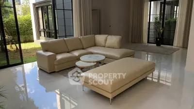 Luxurious living room with elegant beige sofa and large windows overlooking garden