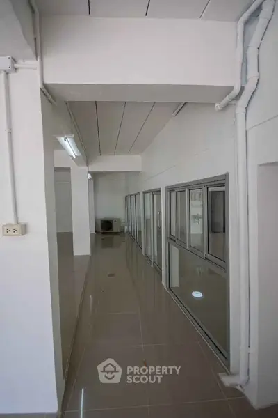 Spacious modern hallway with sleek tiled flooring and glass doors