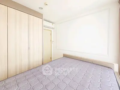 Bright minimalist bedroom with built-in wardrobe and air conditioning unit.