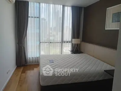 Modern bedroom with large window and city view, featuring a comfortable bed and stylish decor.