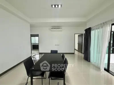 Spacious modern dining area with sleek black table and chairs, large windows, and minimalist design.