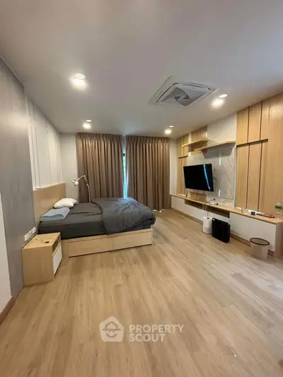 Spacious modern bedroom with wooden flooring and sleek built-in storage