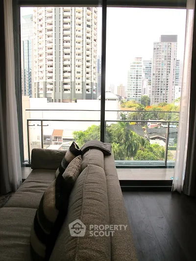 Modern living room with large windows offering stunning city views and cozy seating area.