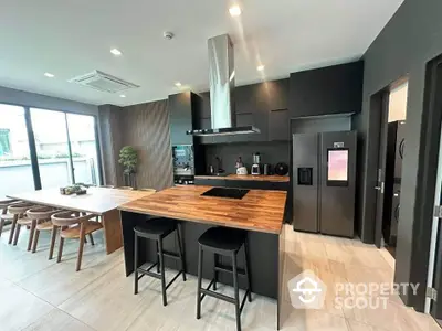 Modern kitchen with island, dining area, and sleek appliances in open layout