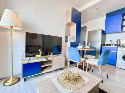 Modern living room with stylish decor, blue accents, and open kitchen layout in a cozy apartment.