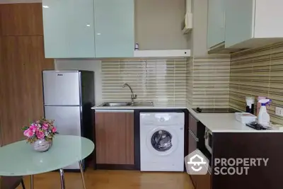 Modern kitchen with sleek cabinetry and integrated appliances, featuring a washing machine and a full-sized refrigerator.