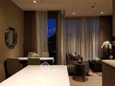 Elegant modern living room with dining area and large windows at night