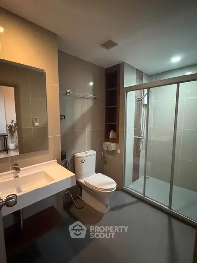 Modern bathroom with sleek design, featuring a glass-enclosed shower and contemporary fixtures.