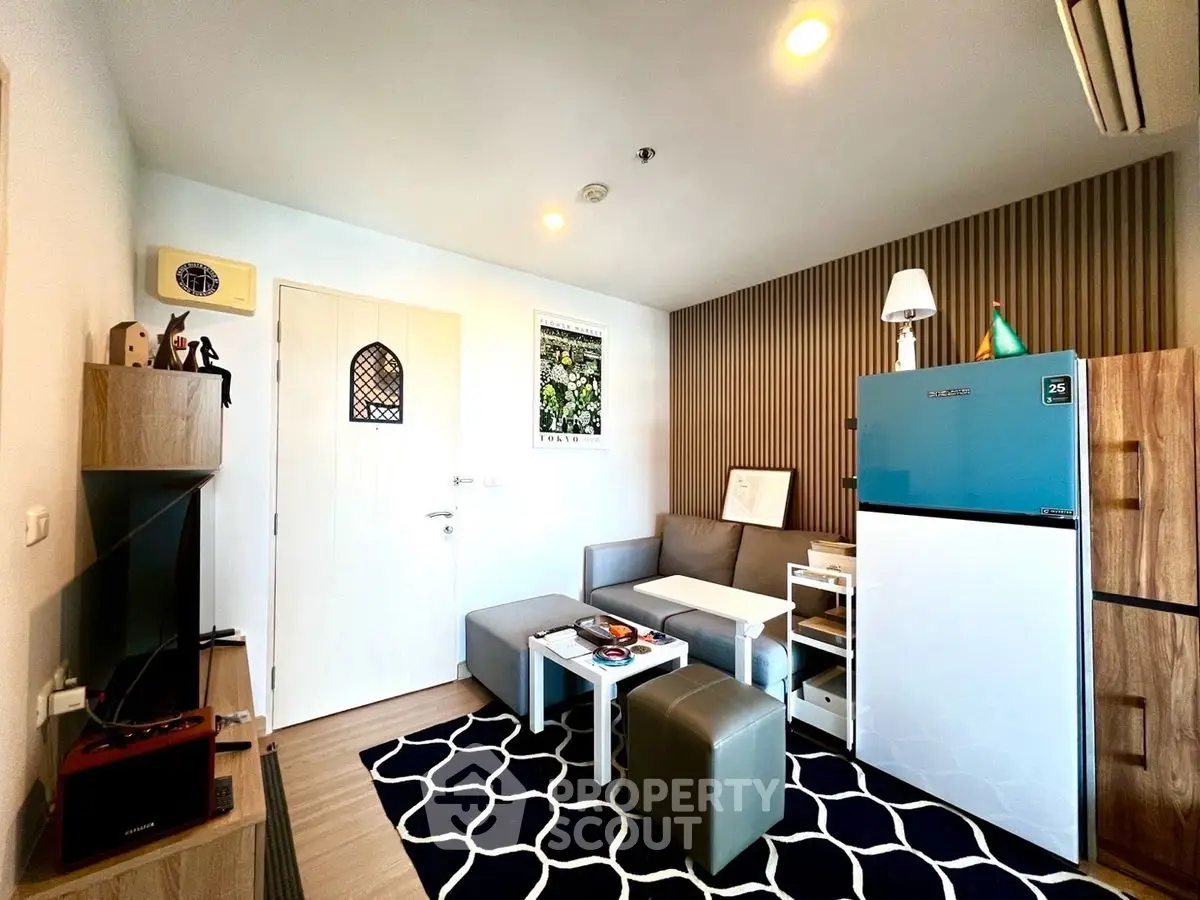 Modern living room with stylish decor and compact layout, featuring a cozy sofa and chic rug.