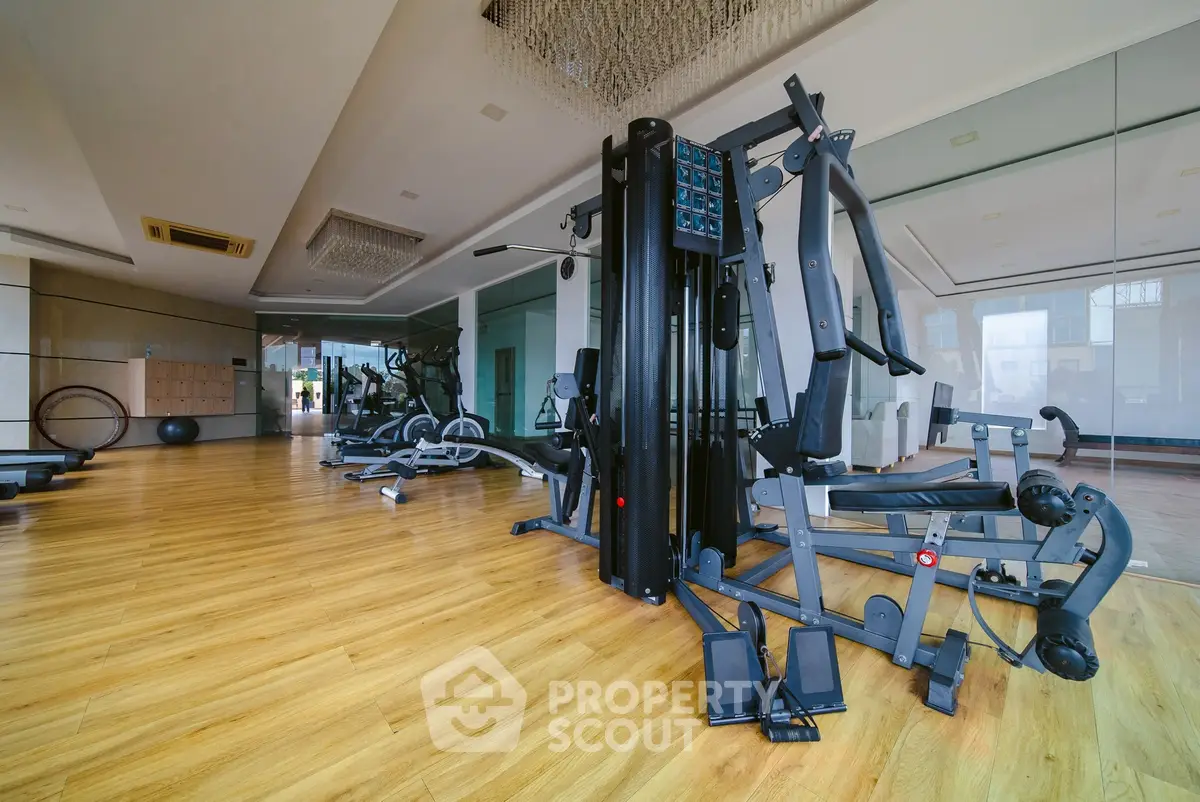 Spacious modern gym with state-of-the-art equipment and wooden flooring.