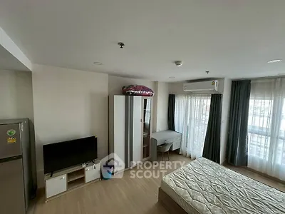 Modern bedroom with balcony, TV, and wardrobe in a bright apartment.