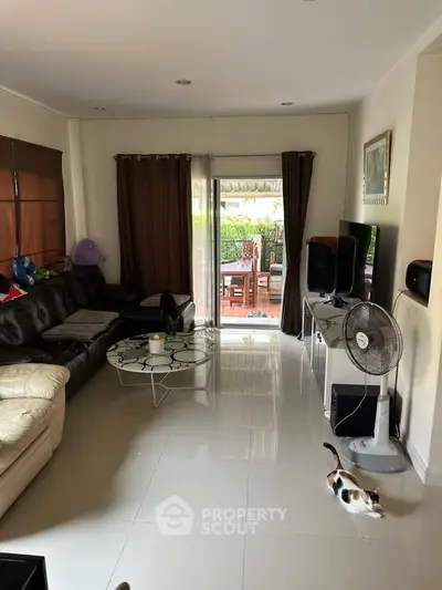Spacious living room with modern decor and garden view, featuring sleek furniture and natural light.