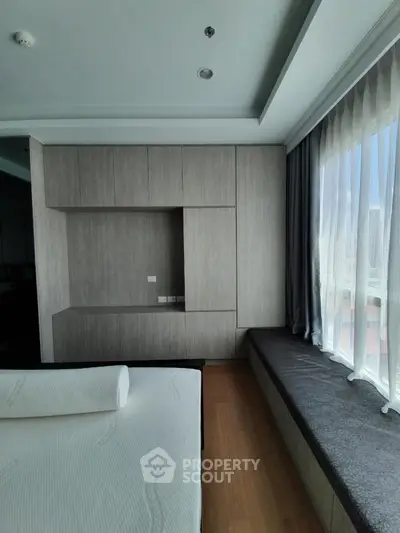 Modern bedroom with built-in storage and large window seating area