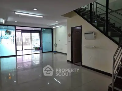 Spacious modern living room with glass doors and staircase, ideal for family gatherings.