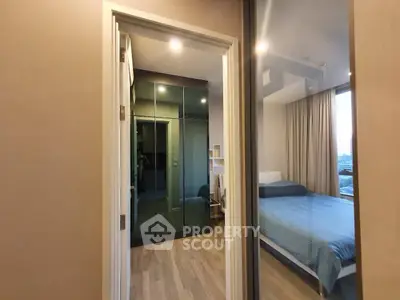Modern bedroom with mirrored wardrobe and city view, featuring sleek design and cozy ambiance.