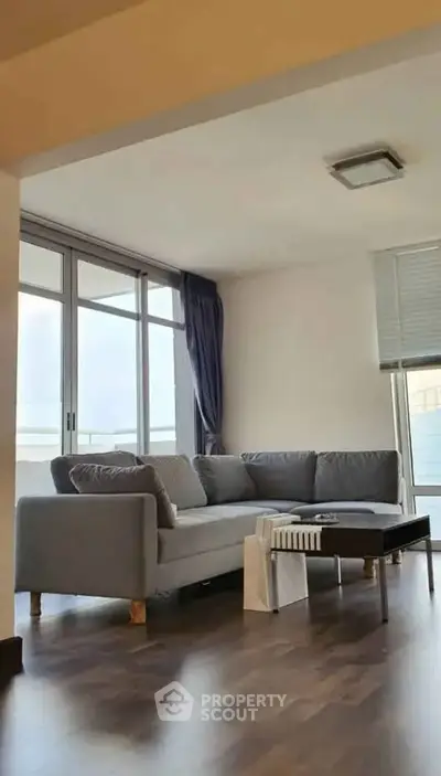Spacious living room with modern gray sofa and large windows
