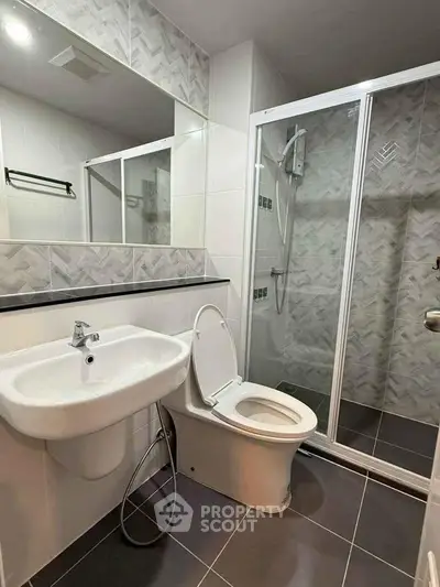 Modern bathroom with sleek design, featuring a glass shower enclosure and stylish tile work.