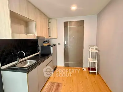 Modern compact kitchen with sleek cabinetry and wood flooring in a cozy apartment setting.