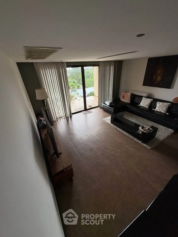 Spacious living room with large windows and modern decor, offering a serene view.