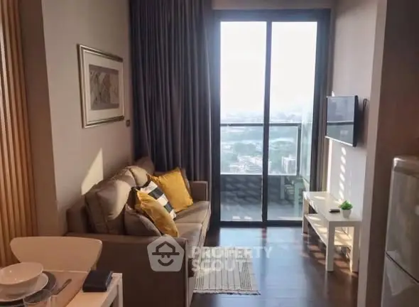 Cozy living room with a view, featuring a sofa, wall art, and a balcony overlooking the cityscape.