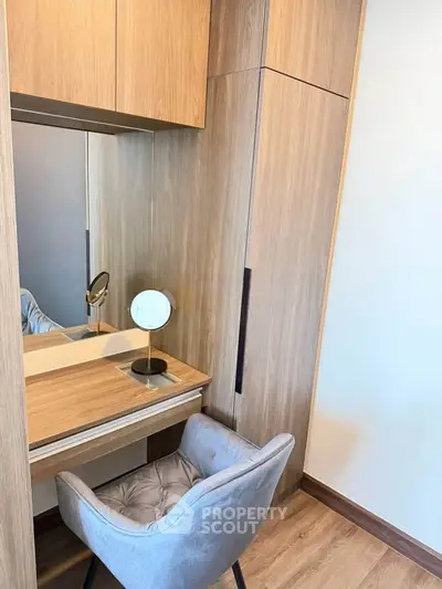 Elegant study nook with wooden cabinetry and plush chair in modern apartment.