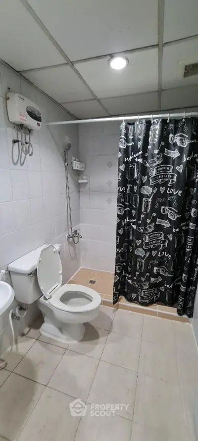 Modern bathroom with shower curtain and white fixtures in a tiled setting.