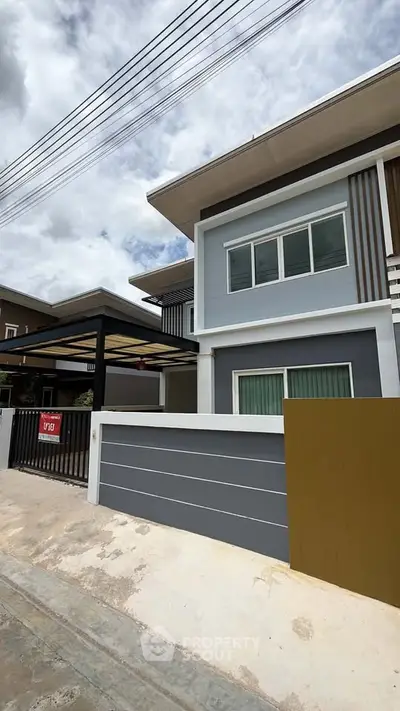 Modern two-story house with sleek design and gated entrance in a suburban neighborhood.