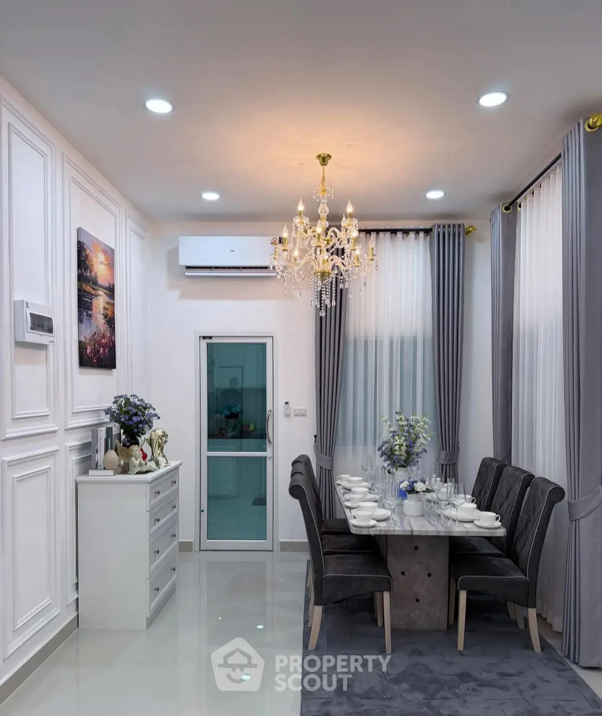 Elegant dining room with chandelier, modern decor, and stylish furniture in a luxurious home setting.