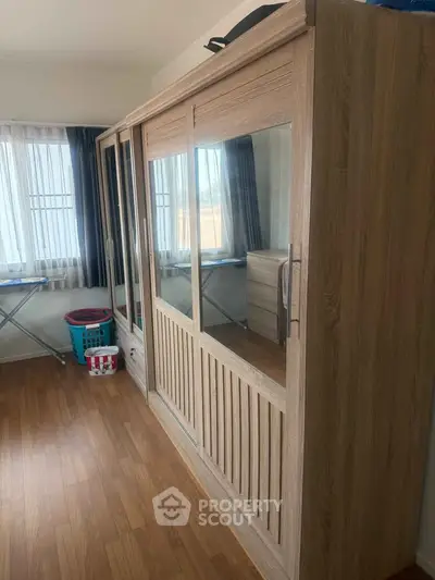 Spacious bedroom with large wooden wardrobe and natural light