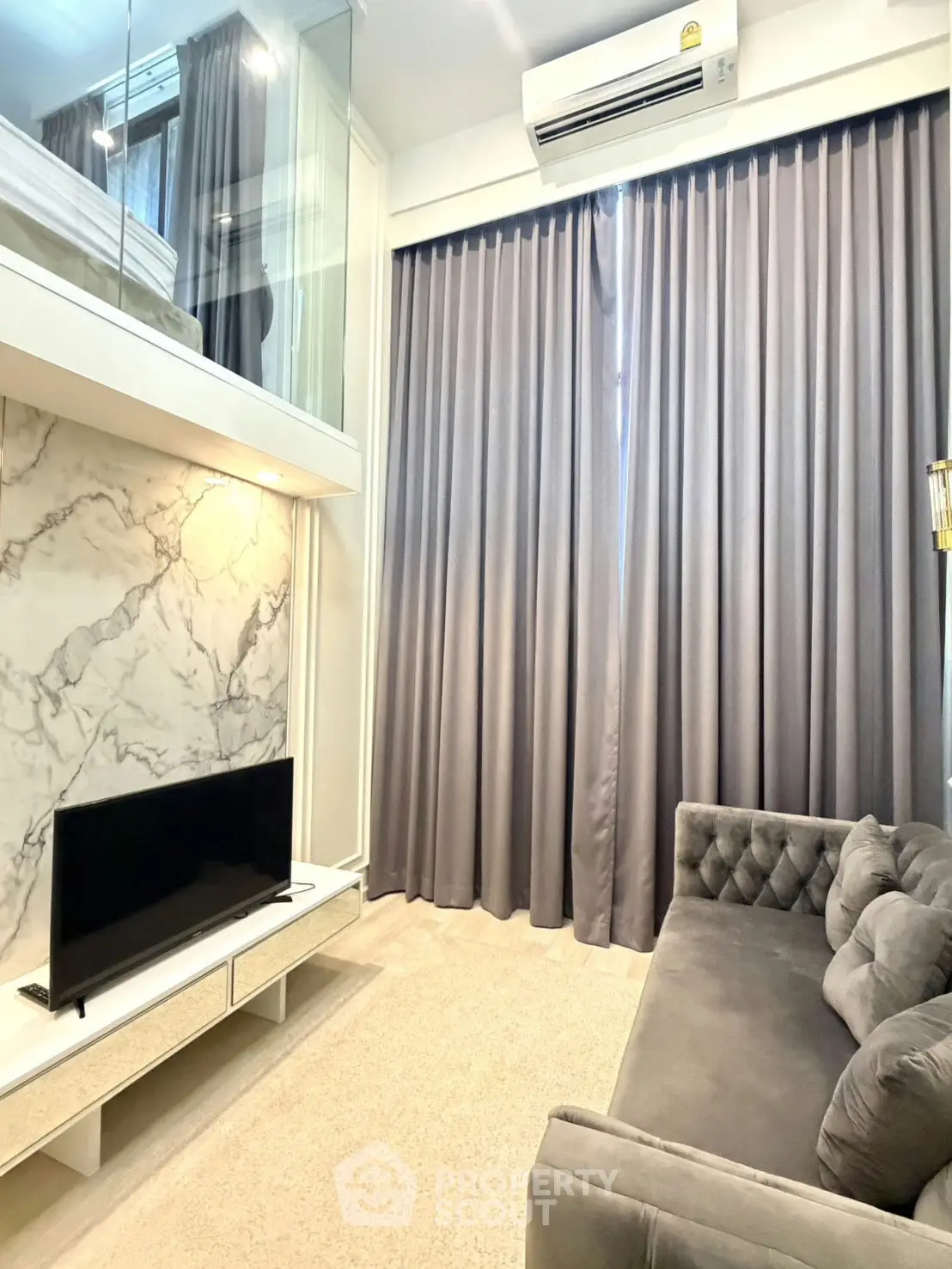 Modern living room with marble accent wall and cozy gray sofa in stylish apartment.
