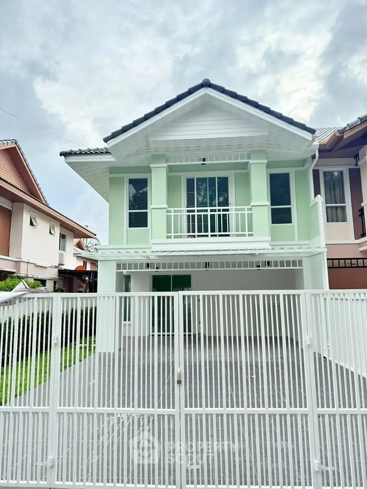 Charming two-story green house with spacious gated driveway and modern design.