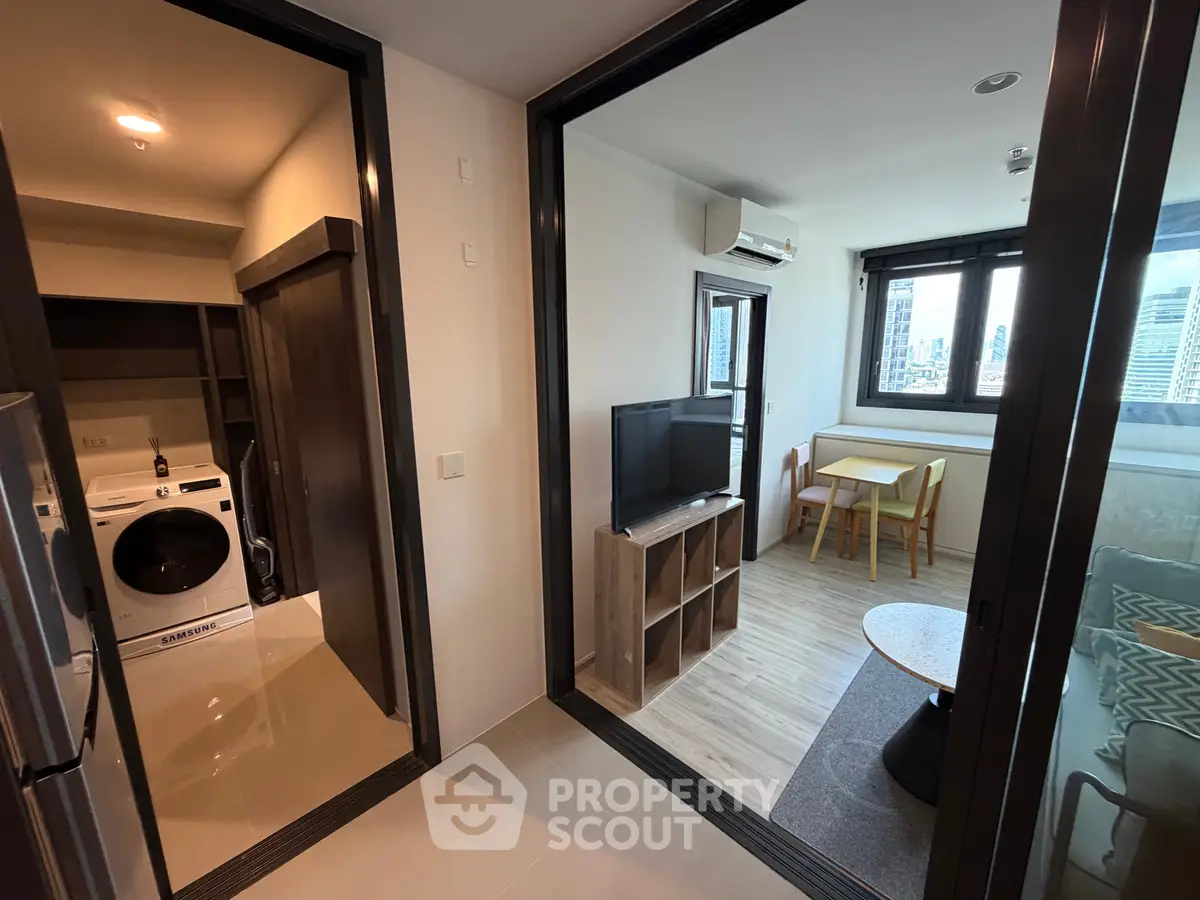 Modern apartment interior with living room, dining area, and laundry space featuring a washing machine.