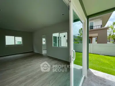 Spacious modern living room with large sliding glass doors opening to a lush green garden.