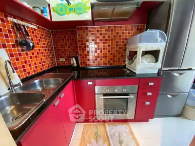 Chic red kitchen with modern appliances and dual sinks, featuring a sleek oven and vibrant backsplash.