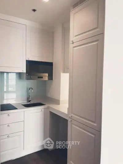 Modern compact kitchen with sleek cabinetry and built-in appliances in a stylish apartment.
