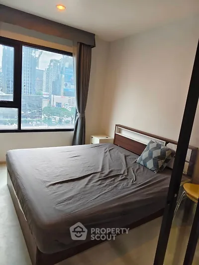 Modern bedroom with city view, featuring a cozy bed and large window.