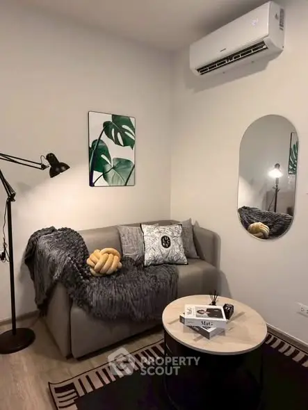 Cozy living room with modern decor, featuring a stylish sofa, chic wall art, and a sleek air conditioning unit.