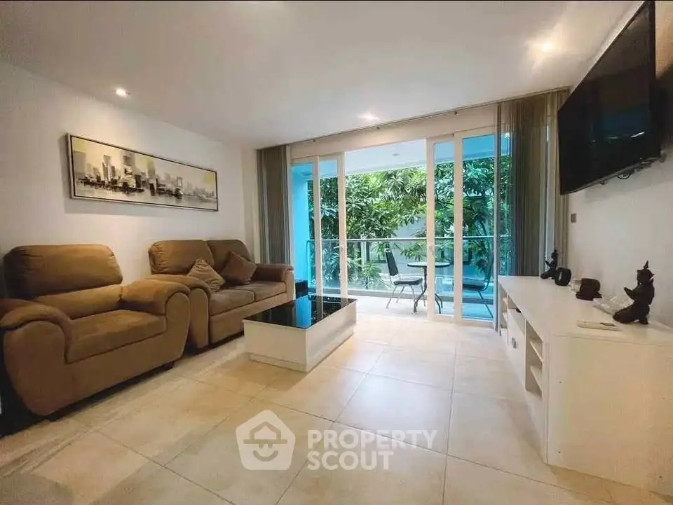 Spacious living room with modern decor and large glass doors leading to a lush garden view.