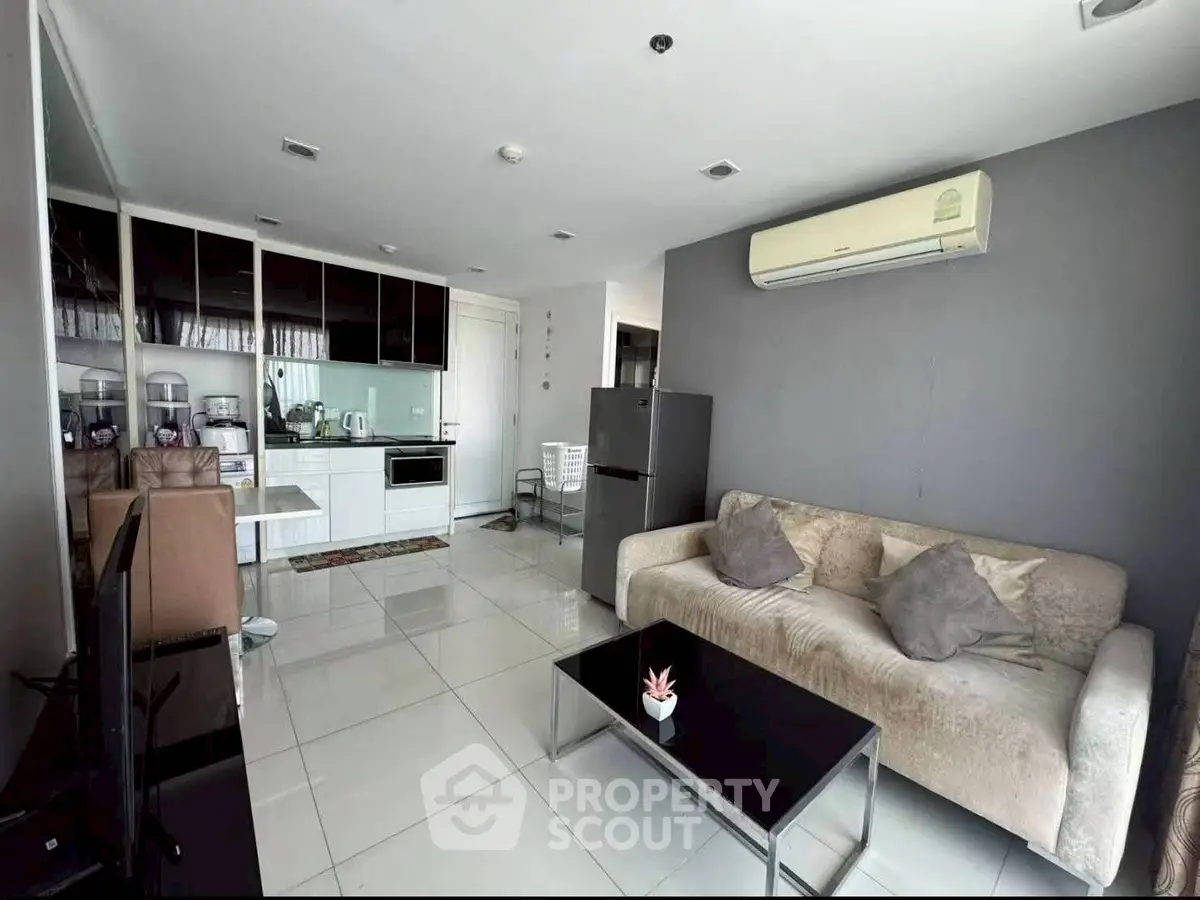 Modern living room with open kitchen, featuring sleek appliances and stylish furniture in a contemporary apartment.
