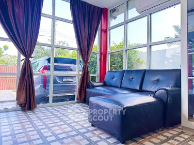 Spacious living room with large windows and modern black sofa, offering a bright and inviting atmosphere.