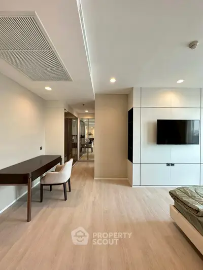 Modern living room with sleek design and wall-mounted TV, featuring wooden flooring and elegant furniture.