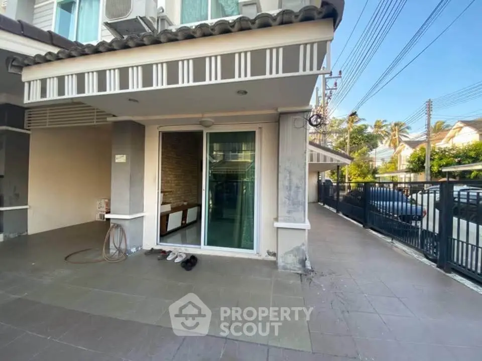 Charming townhouse entrance with tiled patio and sliding glass door, perfect for modern living.